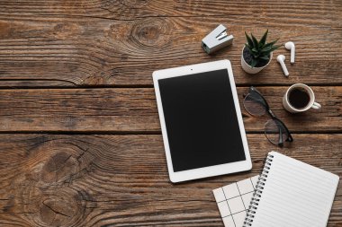 Tablet, bir fincan kahve ve ahşap masadaki kırtasiye malzemeleri.