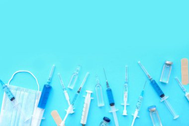 Medical syringes with medicine, ampoules and mask on blue background clipart