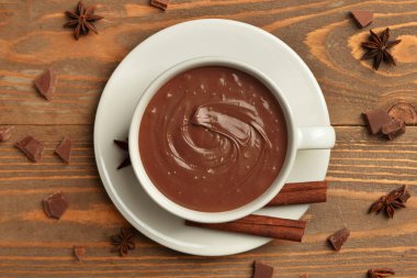Bir fincan lezzetli eritilmiş çikolata, tarçın çubukları ve ahşap arka planda yıldız anason.
