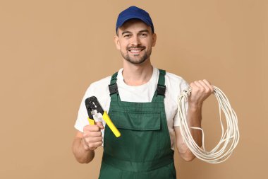 Erkek elektrikçinin bej arka planda tel ve tutacağı olan portresi