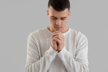 Genç adam gri arka plan üzerinde dua