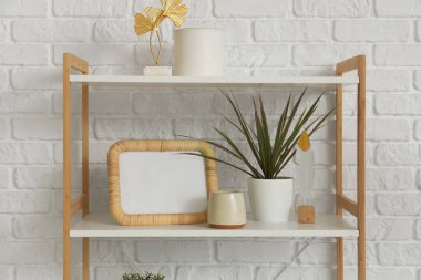 Boş çerçeve, rafta beyaz tuğla duvarın yanında bitki var.