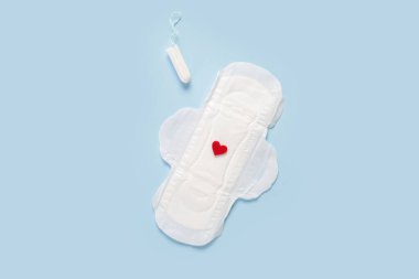 Kırmızı kalbi ve mavi arka planda tamponu olan adet yastığı.