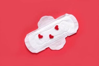 Kırmızı arka planda kalpleri olan adet yastığı.