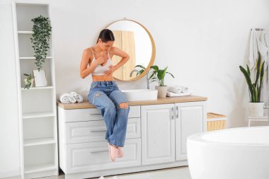 Güzel bir kadın banyoda göğüslerini kontrol ediyor. Kanser farkındalığı kavramı