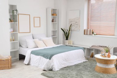 Büyük yataklı, raf üniteli ve çerçeveli aydınlık yatak odasının içi