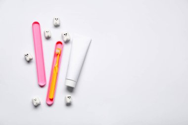 Diş fırçası, diş macunu tüpü ve beyaz arka planda dişler.