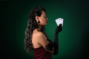 Koyu yeşil arka planda oyun kartları olan güzel bir Afro-Amerikalı kadın.