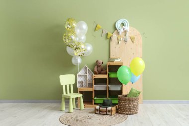 İçinde balonlar, şenlikli kiraz kuşları ve oyuncaklar olan çocuk odasının içi.