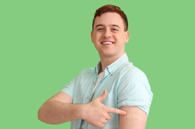 Yeşil arka planda uygulamalı tıbbi yaması olan genç bir adam. Aşılama kavramı