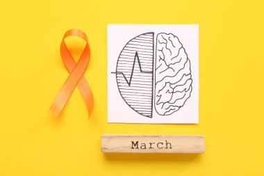 Turuncu kurdeleli beyin çizimleri ve sarı arka planda marş. Çoklu Skleroz Farkındalık Ayı