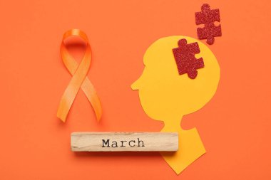 Yapboz parçaları ve turuncu kurdeleli kağıt insan kafası. Çoklu Skleroz Farkındalık Ayı