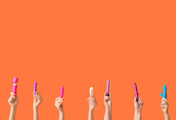 stock image Female hands with different vibrators on orange background