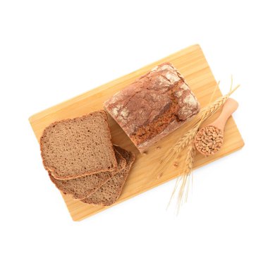 Tahta tahta, dilimlenmiş somun ekmek, buğday dikenleri ve beyaz arka planda tahıllar.