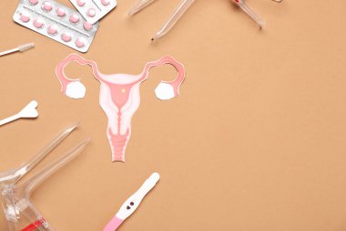 Kahverengi arka planda jinekolojik spekulum, hap ve pap smear testleri olan kağıt rahim.