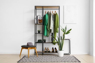 Işık odasının içinde şık kadın kıyafetleri, ayakkabıları ve çiçekleri rafa kaldırın.