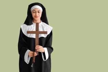 Yeşil arka planda haçlı ve boncuklu genç rahibe.