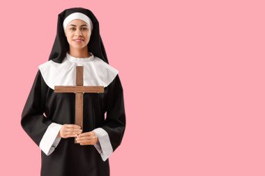 Pembe arka planda haç çizen genç rahibe