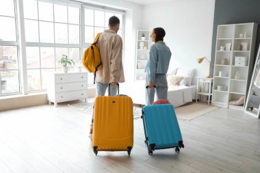 Çantalı iki genç turist otel odasını ve arka manzarayı kontrol ediyor.