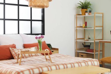 İçinde yatak, pencere, raf ünitesi ve laleli tepsi olan rahat bir yatak odası.