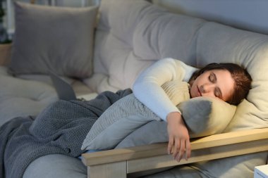 Ekoseli genç bir kadın akşamları kanepede uyuyor.