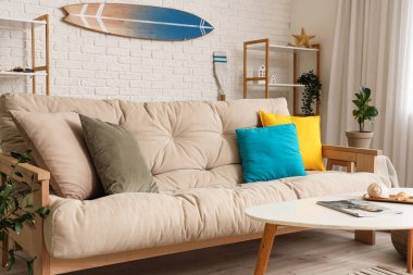 Beyaz kanepe ve sörf tahtasıyla aydınlık oturma odasının içinde.