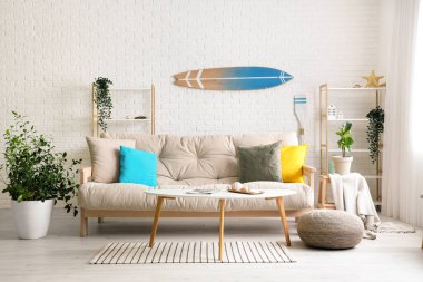 Beyaz kanepe ve sörf tahtasıyla aydınlık oturma odasının içinde.