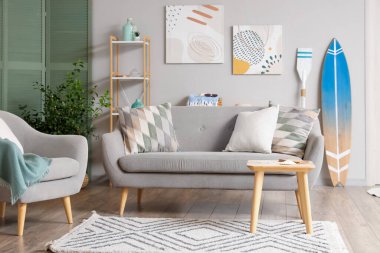 Gri kanepe ve sörf tahtasıyla modern oturma odasının içinde.