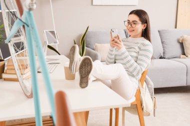 Evde cep telefonu kullanan kız öğrenci.