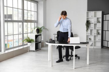 Ofiste baş ağrısı çeken yorgun genç bir işadamı.