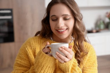 Mutfakta kahve fincanı olan güzel genç bir kadın, yakın plan.