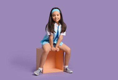 Leylak arka planında poz veren zarif küçük bir kızın portresi.