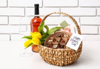 Anneler günü için ışık masasında hediye sepeti, lale çiçekleri ve bir şişe şarap.