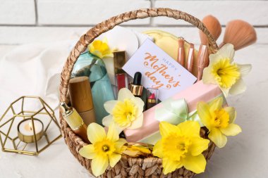 Süslü kozmetik ürünleri, aksesuarlar ve narsist çiçeklerle dolu hediye sepeti. Anneler Günü kutlaması için ışık masasında, yakın plan.