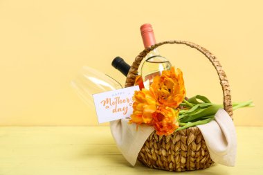 Anneler Günü kutlamaları için şarap, cam ve lale dolu sepet renkli ahşap masada.