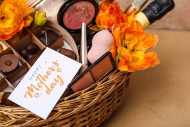 Anneler Günü kutlaması için içinde şeker, kozmetik ve lale çiçekleri olan hediye sepeti renk masasında, yakın plan.