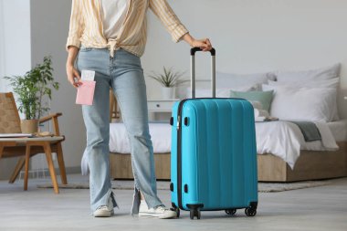 Bavullu kadın, pasaport ve biletler açık otel odasında.