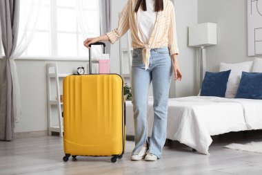 Bavullu kadın, pasaport ve biletler açık otel odasında.