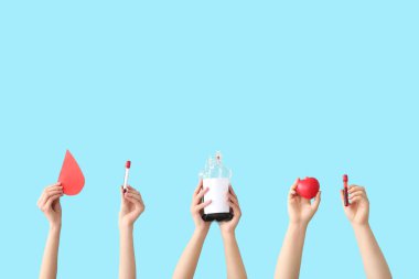 Kan torbaları, test tüpleri, kalpler ve mavi arka planda kağıt kan damlaları tutan kadın elleri. Kan bağışı konsepti