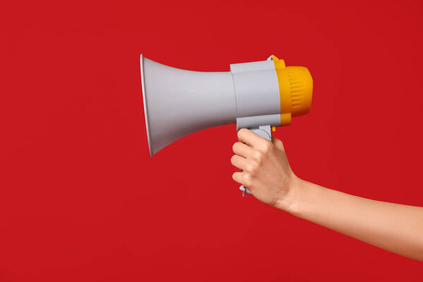 Женщина-спасатель держит мегафон на красном фоне