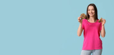 Mavi arka planda lezzetli kurabiyeleri olan genç ve güzel bir kadın.