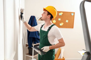 Macun bıçaklı erkek dekoratör odada çalışıyor.