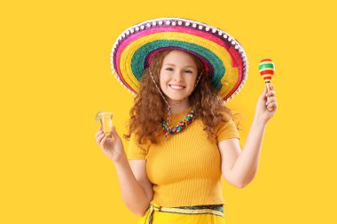 Sarı arka planda tekila ve marakas olan mutlu Meksikalı kadın.