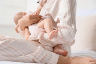 Mutlu anne küçük bebeğini yatak odasında emziriyor.