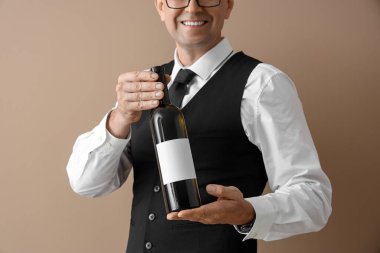 Olgun şarap garsonu bej arka planda bir şişe şarap, yakın plan.