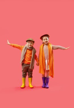 Kırmızı arka planda lastik çizmeli küçük çocuklar