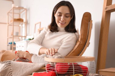 Evde iğneli çorap ören genç bir kadın.