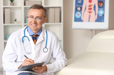 Tıbbî ofiste panosu olan olgun bir doktor.