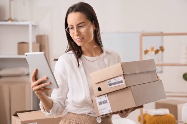 Depo deposunda tablet bilgisayarı ve paketleri olan kadın satıcı