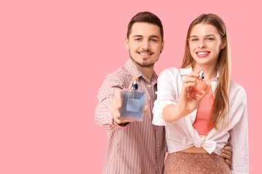Pembe arka planda parfüm şişeleri olan genç bir çift.